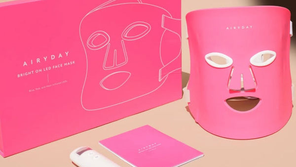 Pink facial mask with packaging and remote control on a beige background