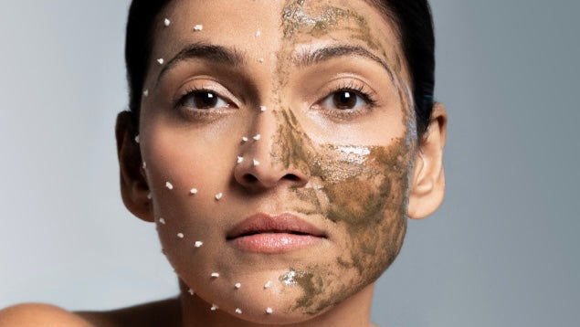 Woman with a mud mask on her face against a gray background