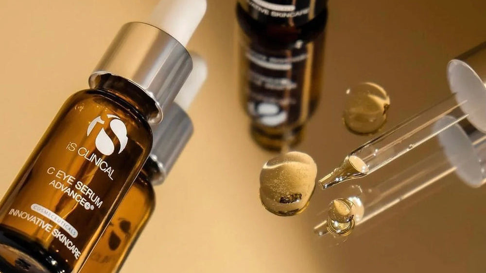 Two bottles of IS Clinical eye serum with droppers on a beige background