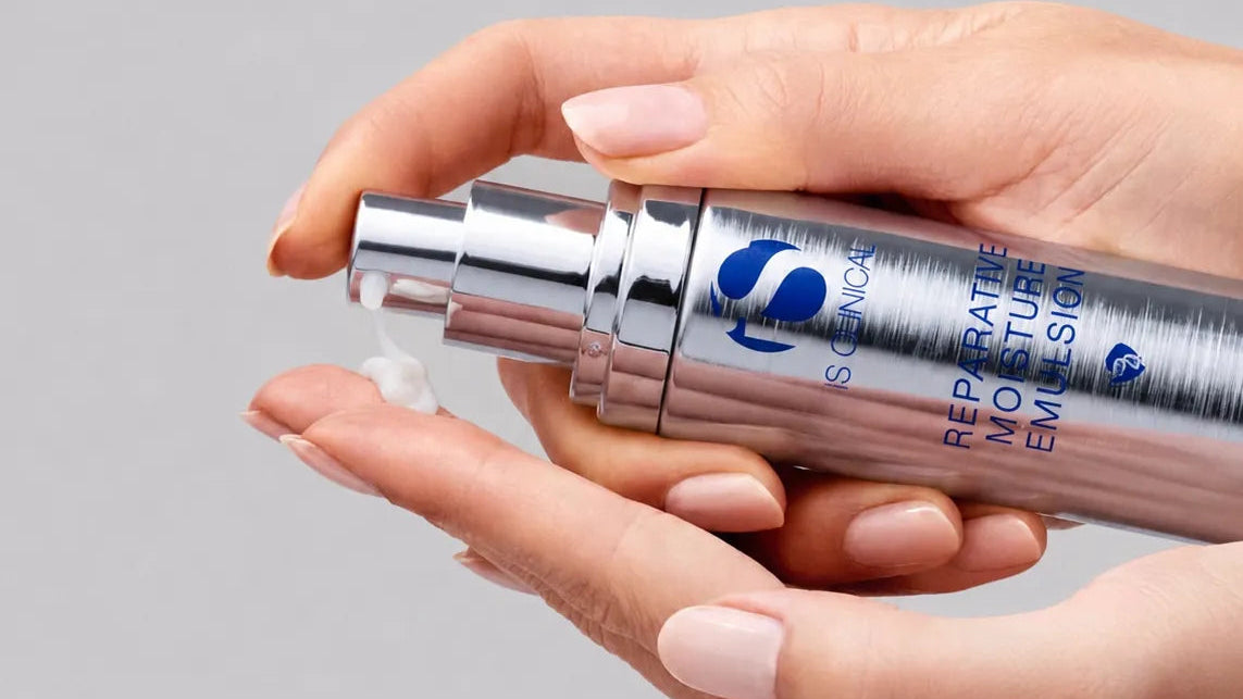 Hand holding a skincare product with a gray background
