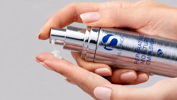Hand holding a skincare product with a gray background