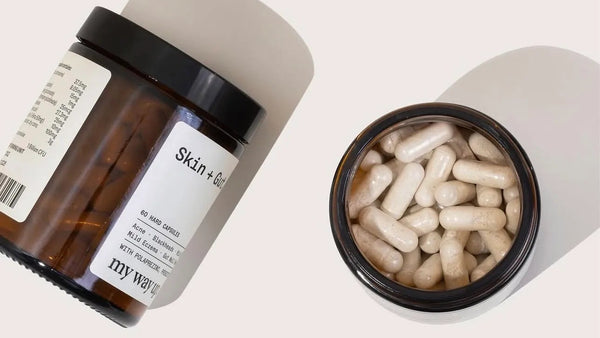 Supplement containers labeled 'Skin + Gut' on a light background