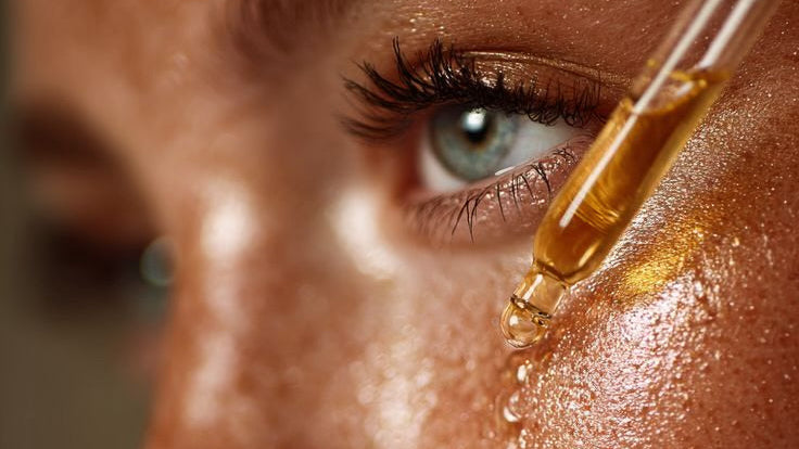Close-up of a person's face with a dropper applying a liquid to their skin.